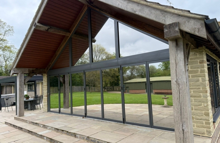 Large bifold patio doors with solar control window film installed, helping to reduce heat build up and glare while preserving clear outdoor views in a modern home extension