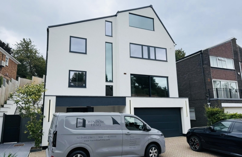 Modern white residential property with large glazed windows fitted with solar control window film, installed by TS Window Films to improve privacy, glare reduction and energy efficiency