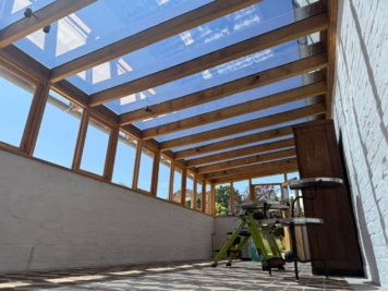 Wooden conservatory interior with roof glazing treated with solar control window film, helping reduce glare and overheating while preserving clear sky views.