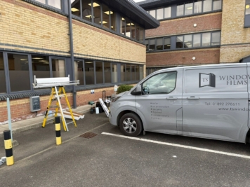 TS Window Films installation team applying privacy window film to commercial office windows, with branded van and equipment on site in Sussex