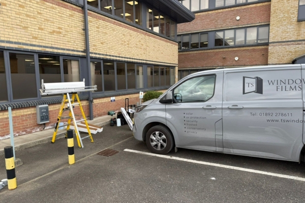 TS Window Films installation team applying privacy window film to commercial office windows, with branded van and equipment on site in Sussex