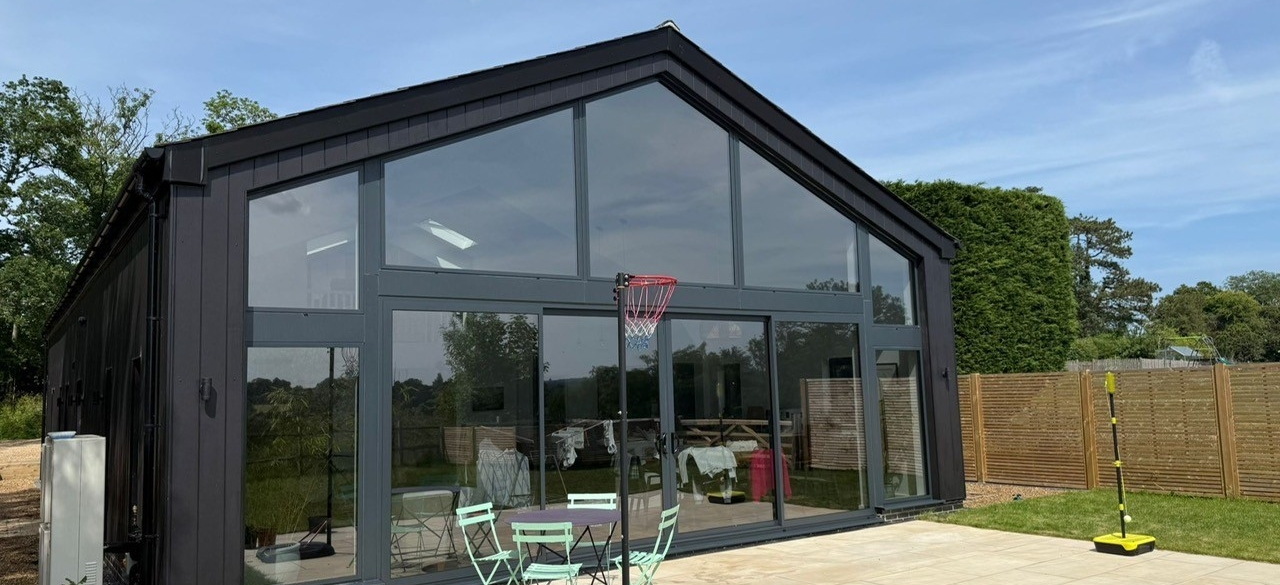 Large residential garden room with floor to ceiling glazing fitted with solar control window film, improving heat reduction and glare control for modern home extension