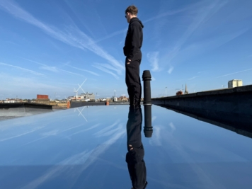 Commercial roof glazing fitted with reflective solar control window film, demonstrating heat reduction and mirrored finish against city skyline backdrop