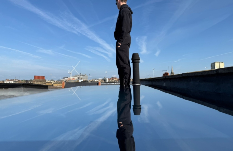 Commercial roof glazing fitted with reflective solar control window film, demonstrating heat reduction and mirrored finish against city skyline backdrop